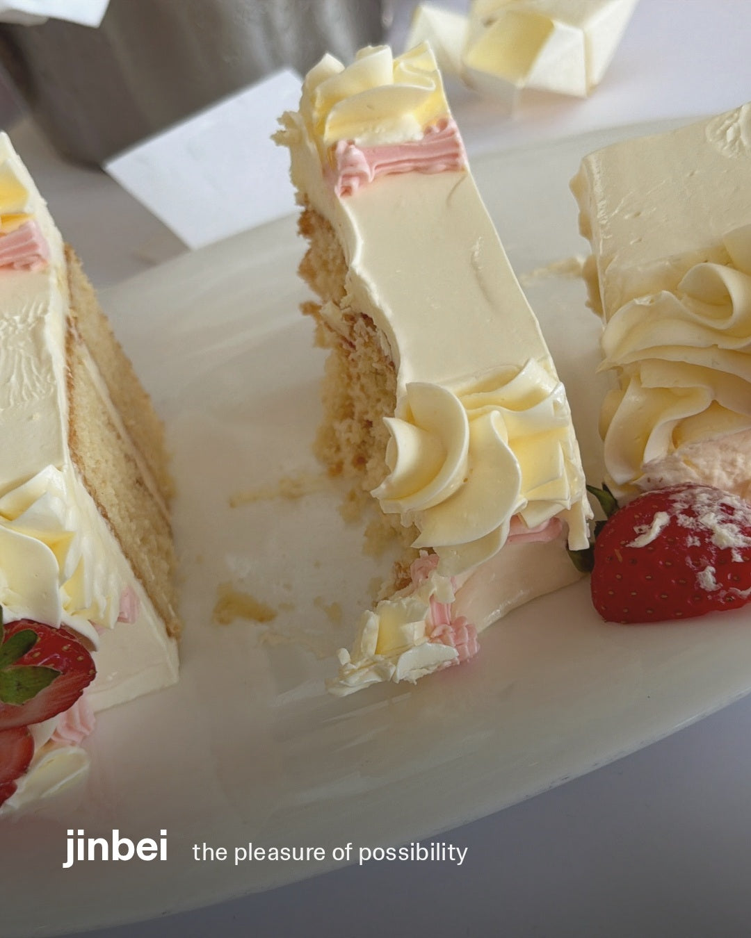 A slice of layered cake with cream and strawberries, styled with the jinbei wordmark and the title ‘the pleasure of possibility’.